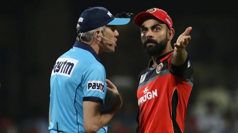 An umpire arguing with Virat Kohli during a cricket match