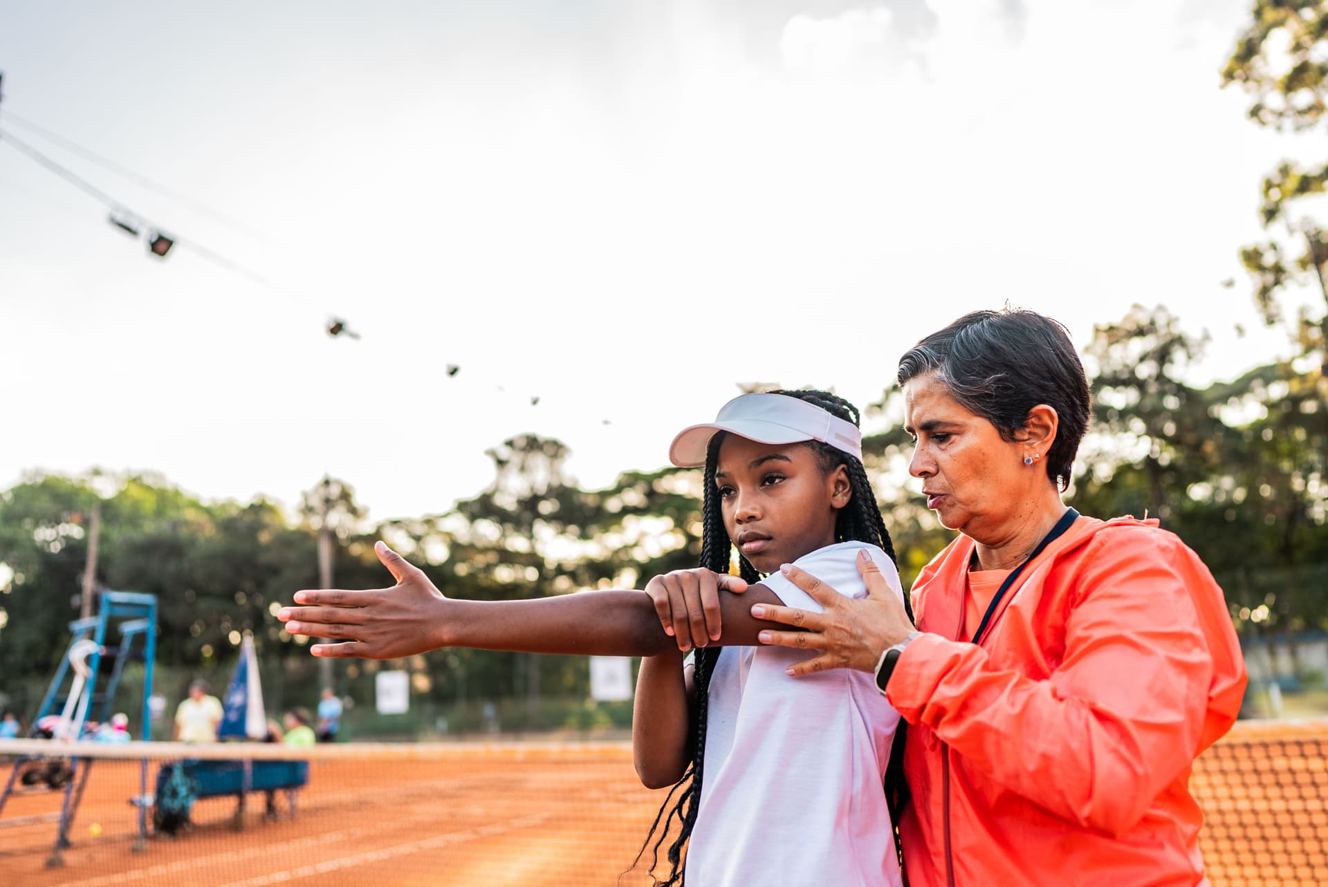 Instructor helping tennis player on tennis beach venue