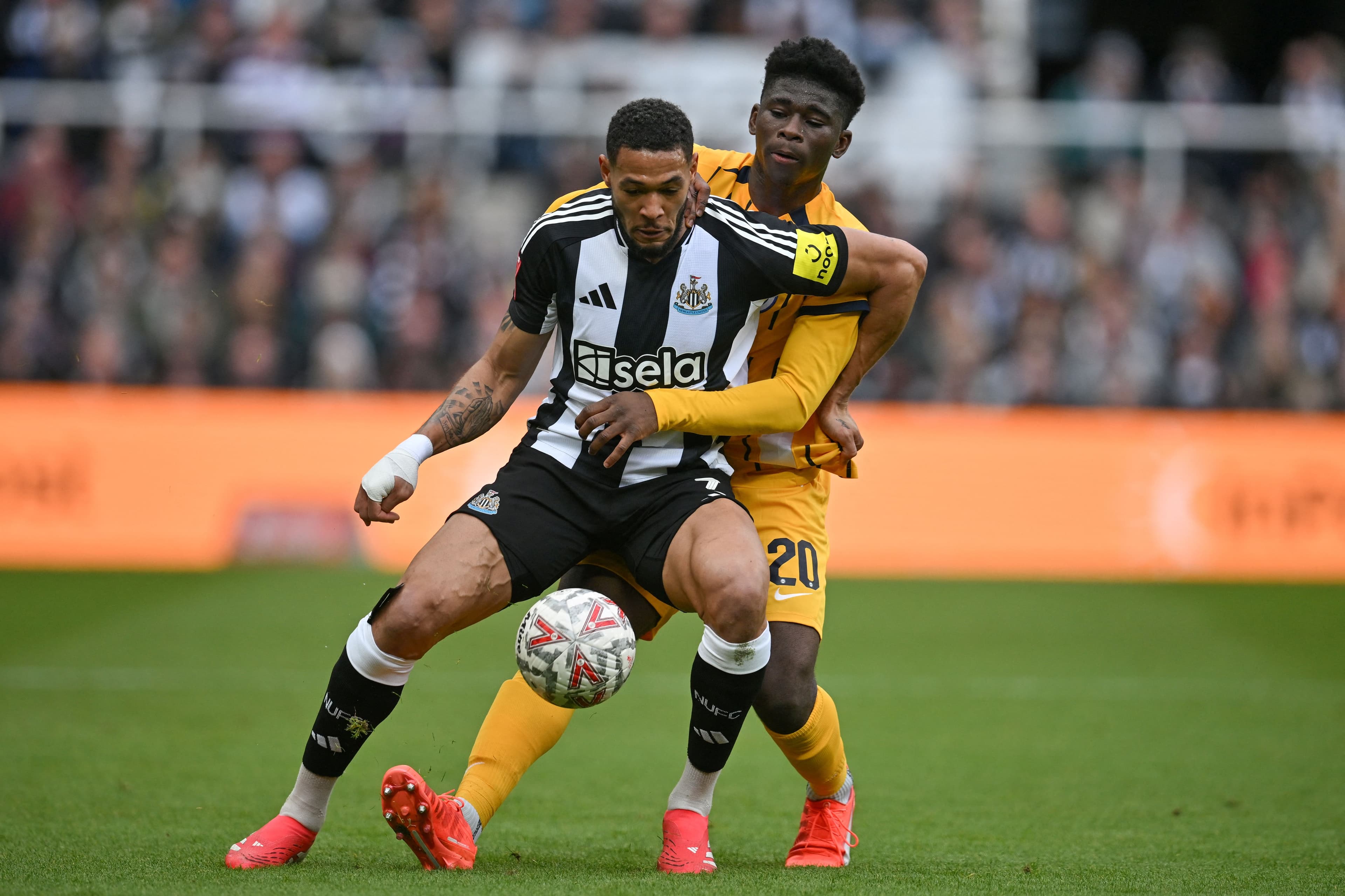 Joelinton fights for the ball with Carlos Baleba