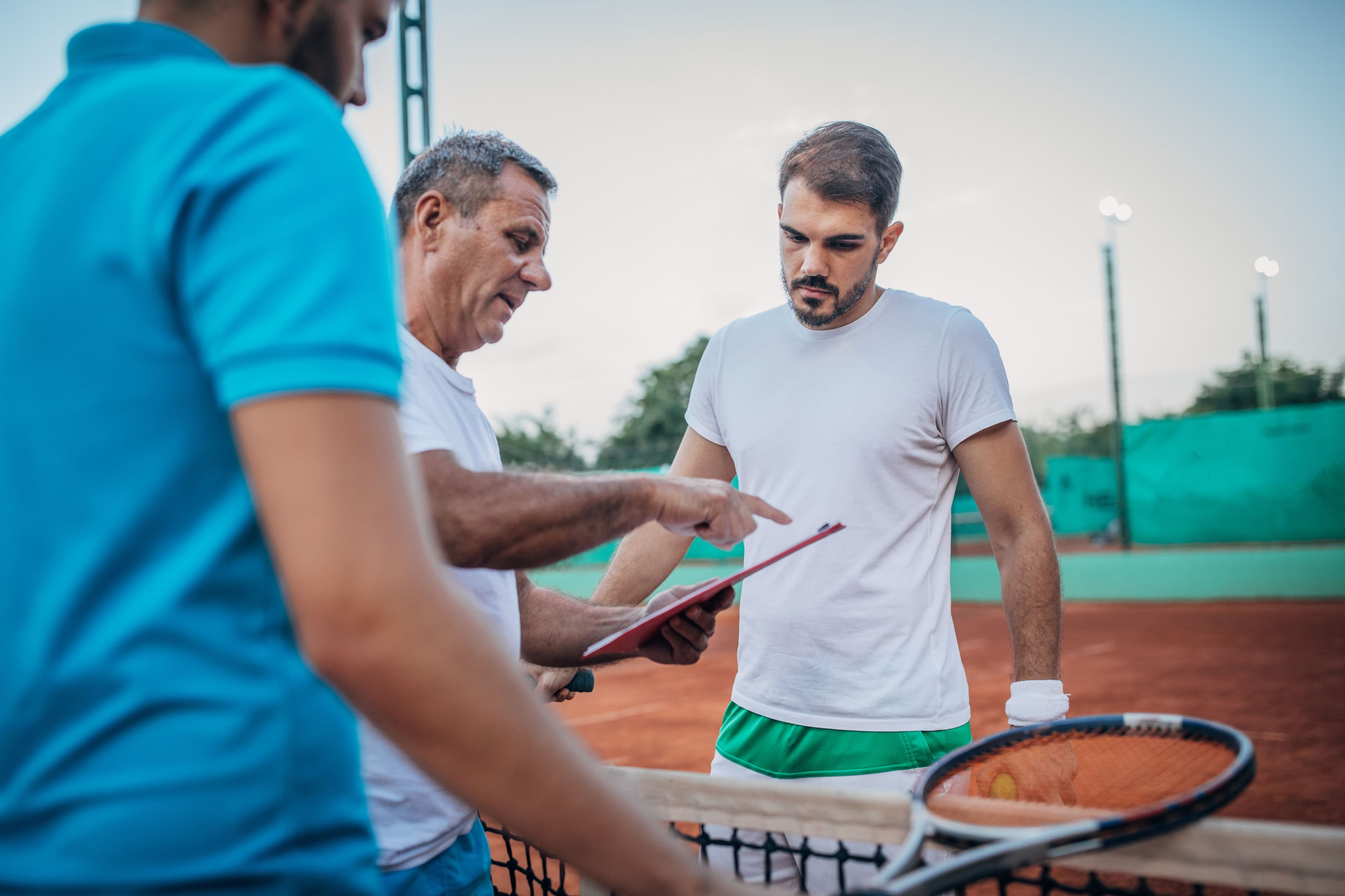 Tennis players standing with tennis coach on court
