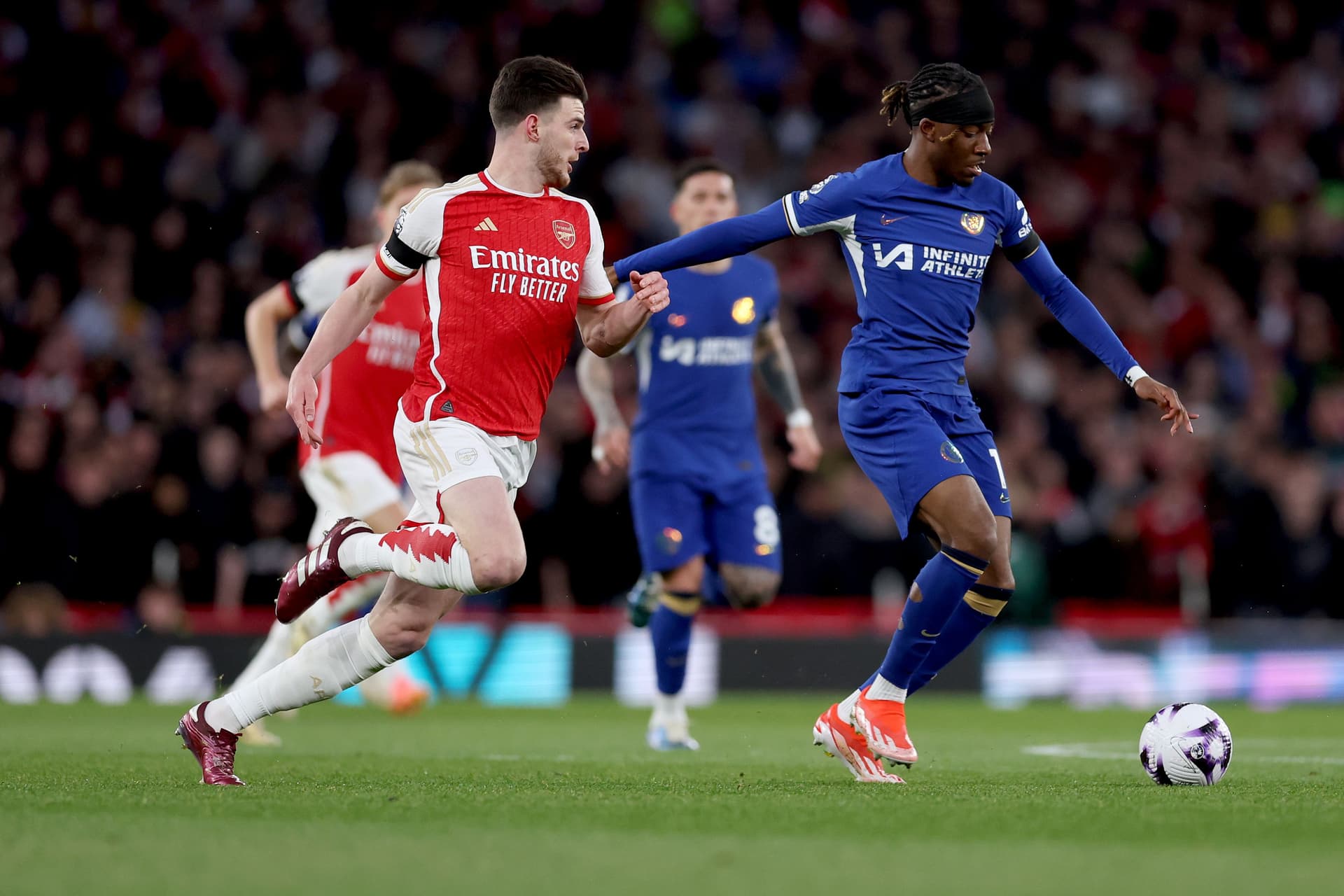 Declan Rice of Arsenal battles for possession with Noni Madueke of Chelsea during the Premier League match between Arsenal FC and Chelsea FC