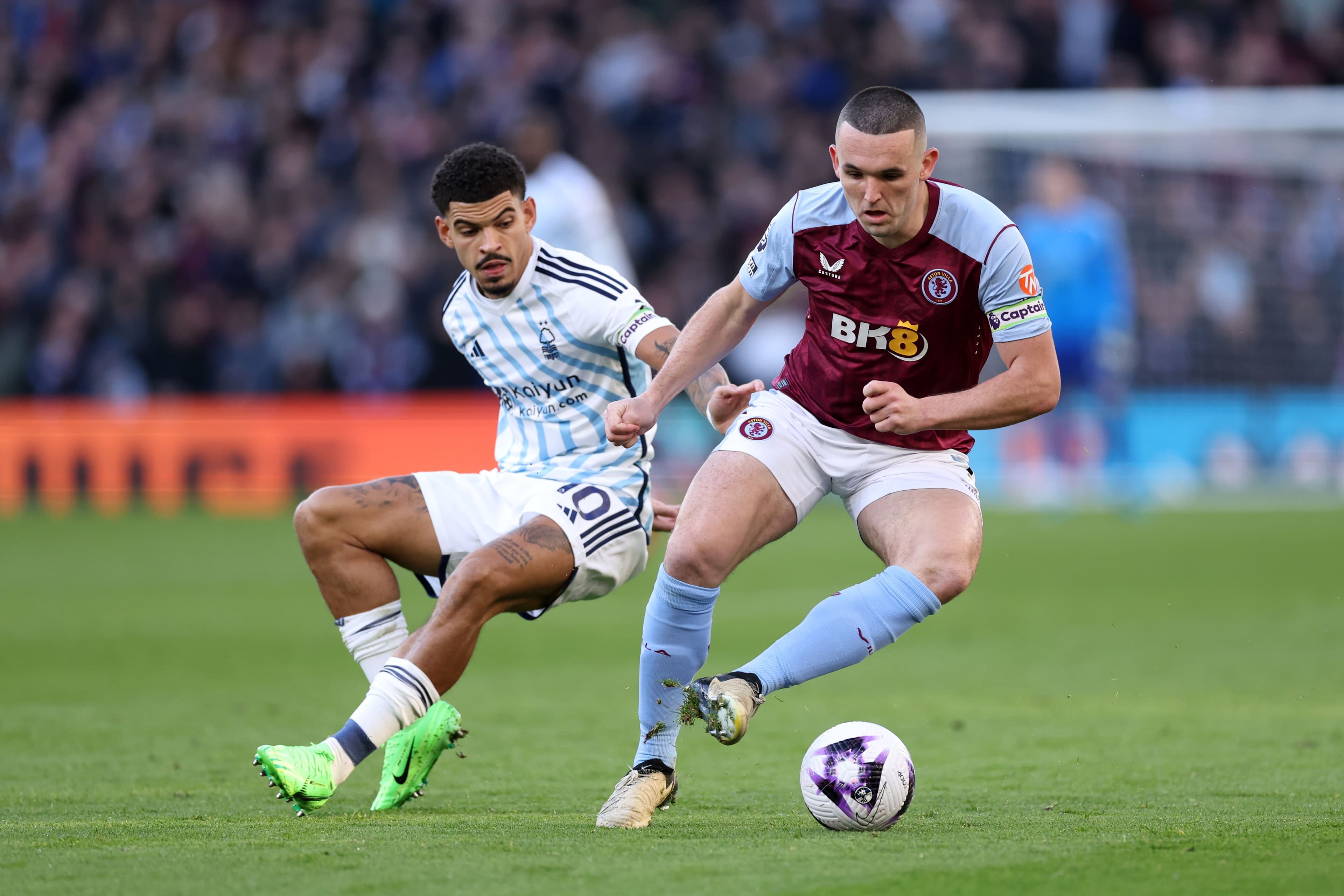 John McGinn of Aston Villa runs with the ball whilst under pressure from Morgan Gibbs-White of Nottingham Forest