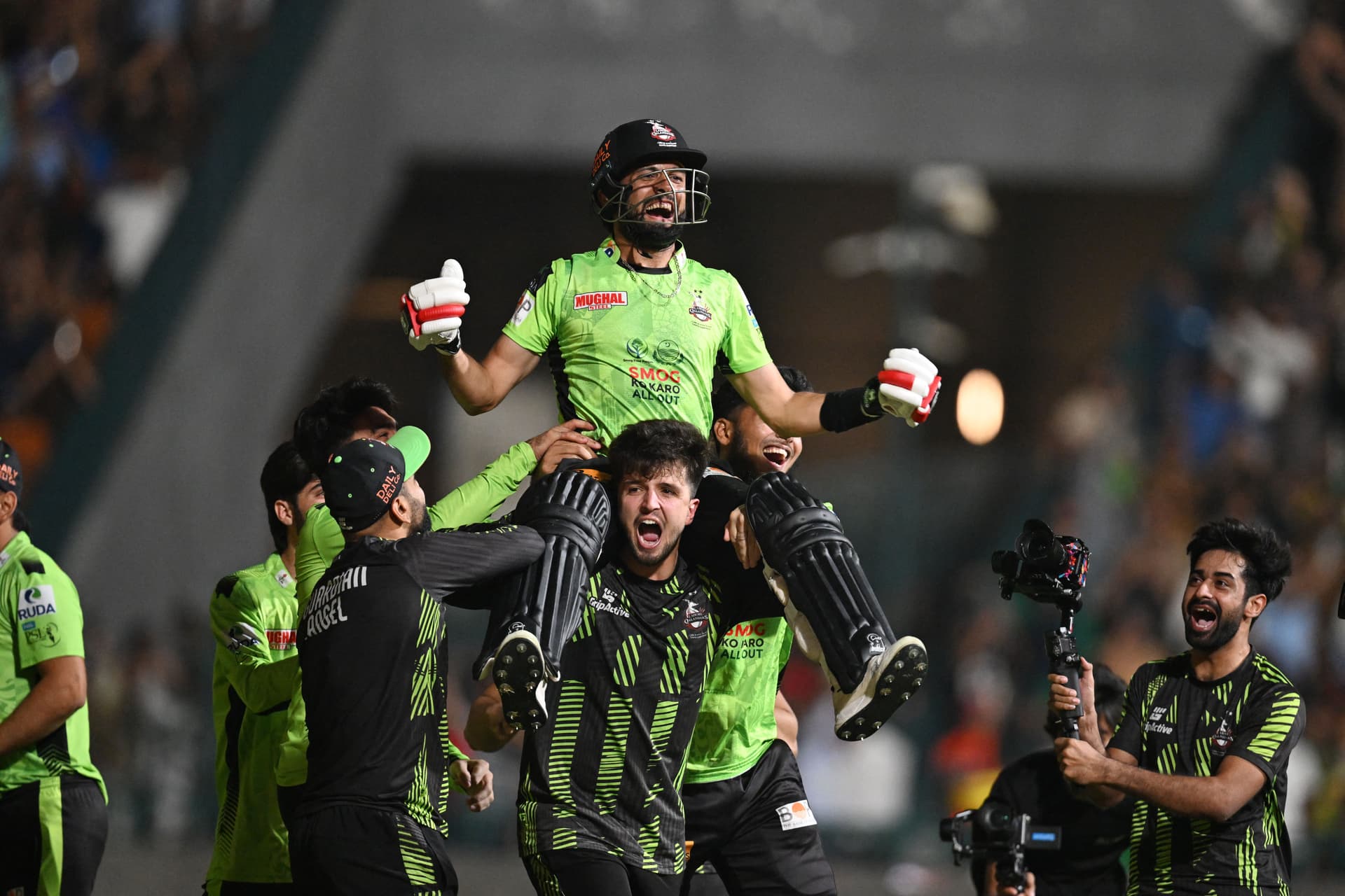 Lahore Qalanders' players carry teammate Sikandar Raza as they celebrate after their victory