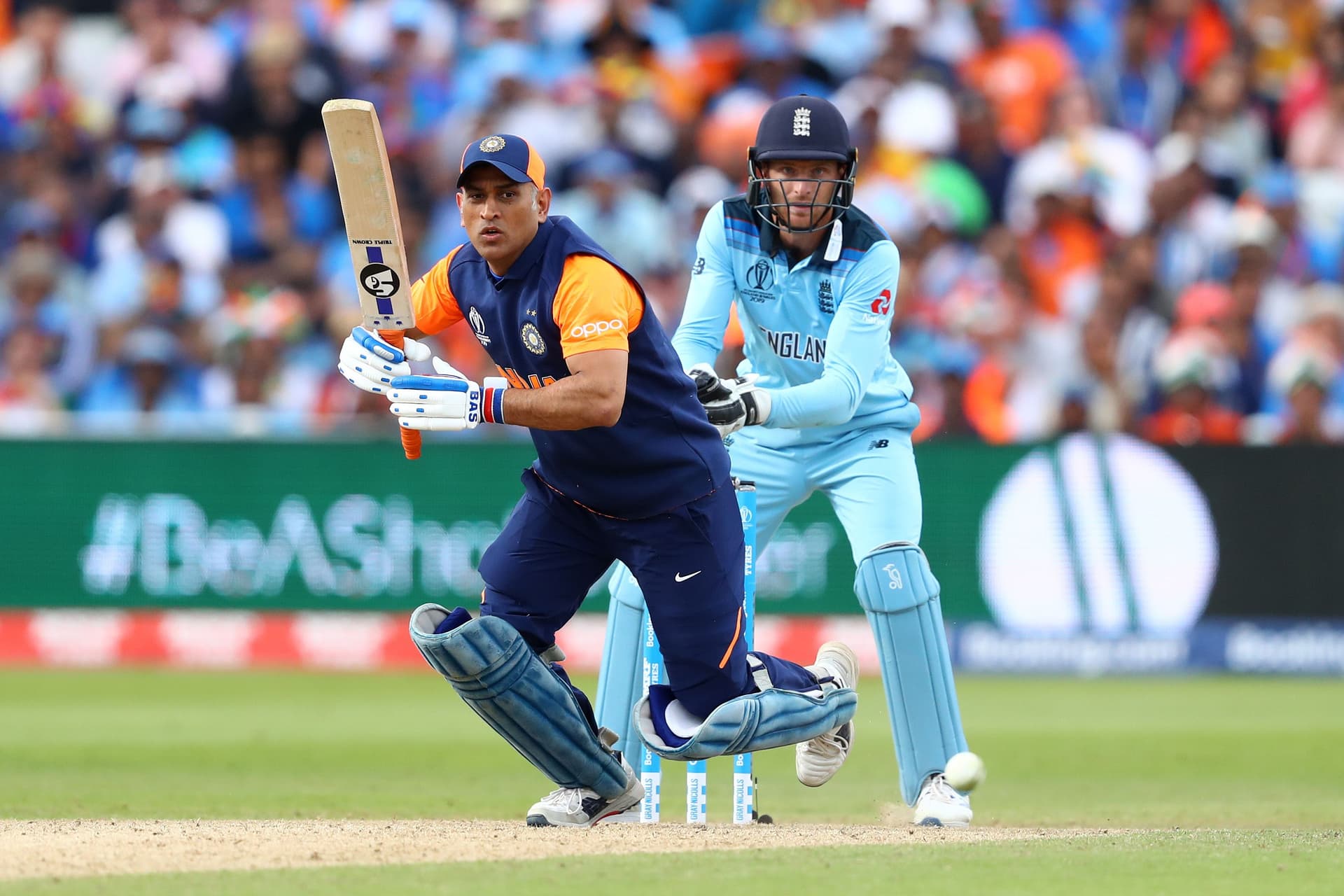 MS Dhoni of India plays to long on as England wicketkeeper Jos Buttler looks on