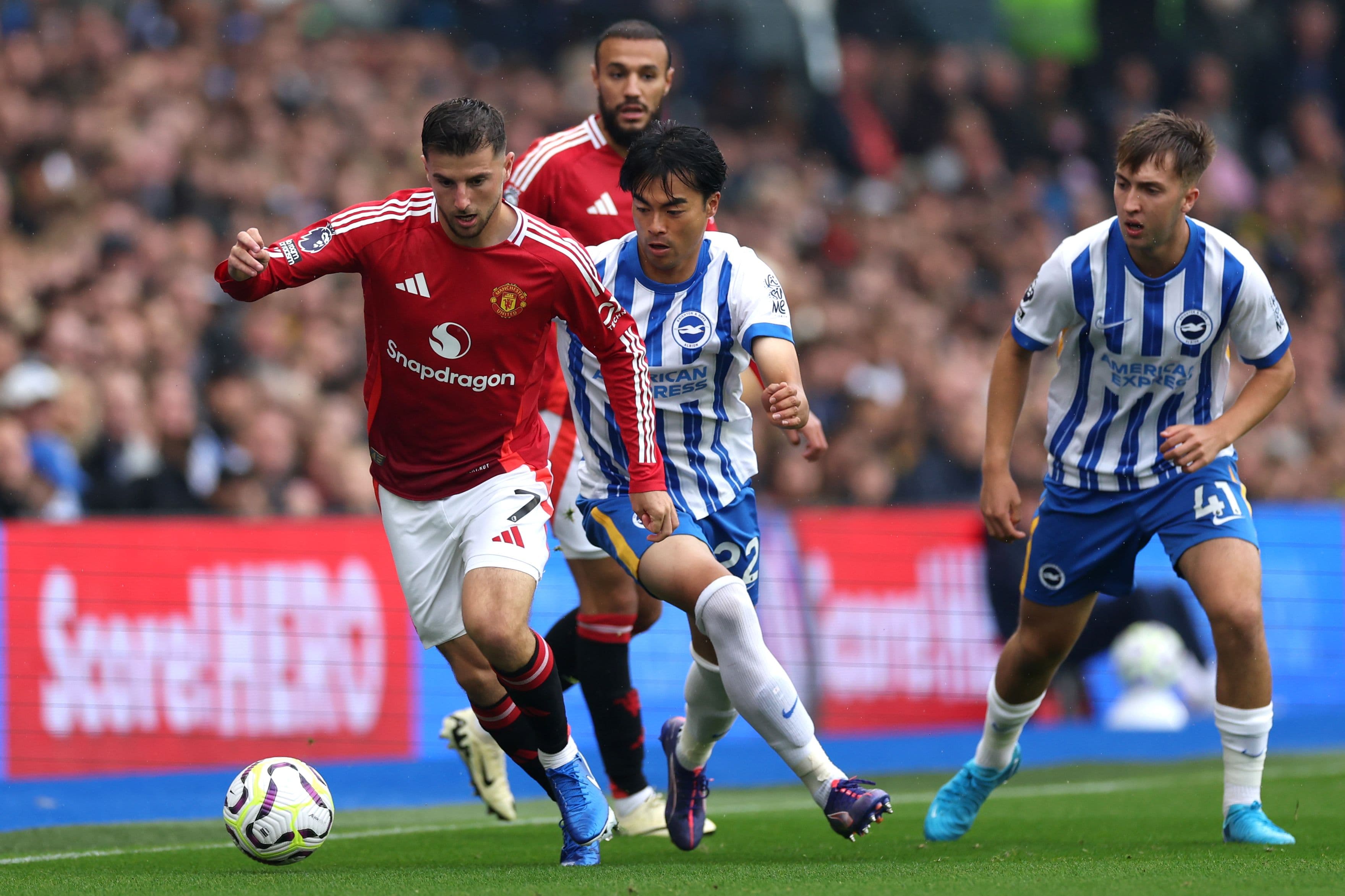 Mason Mount runs with the ball under pressure from Kaoru Mitoma & Hove Albion