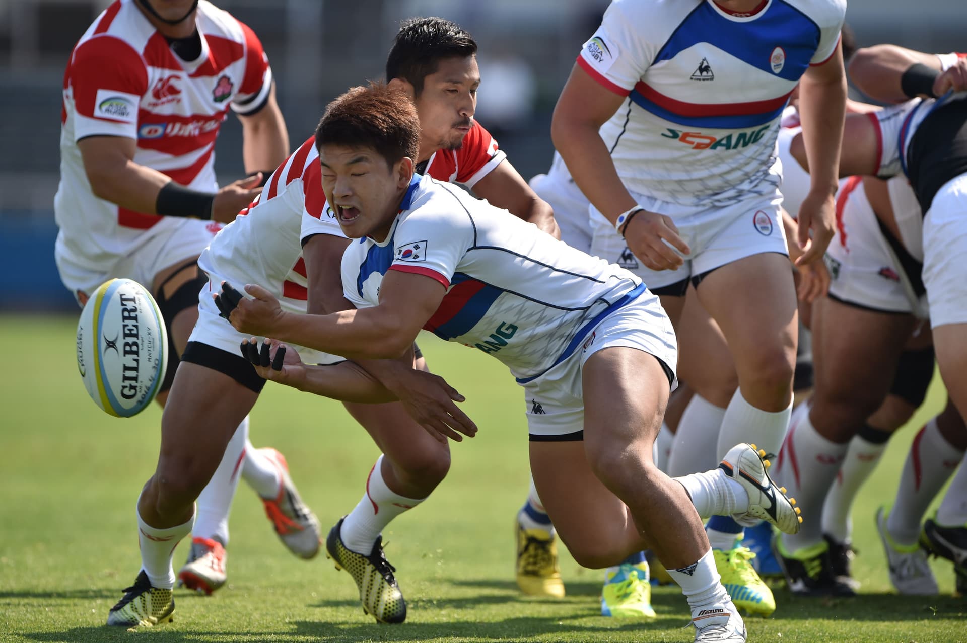 South Korea's scrum-half Shin Ki Cheol (C) is tackled by Japan's scrum-half Keisuke Uchida