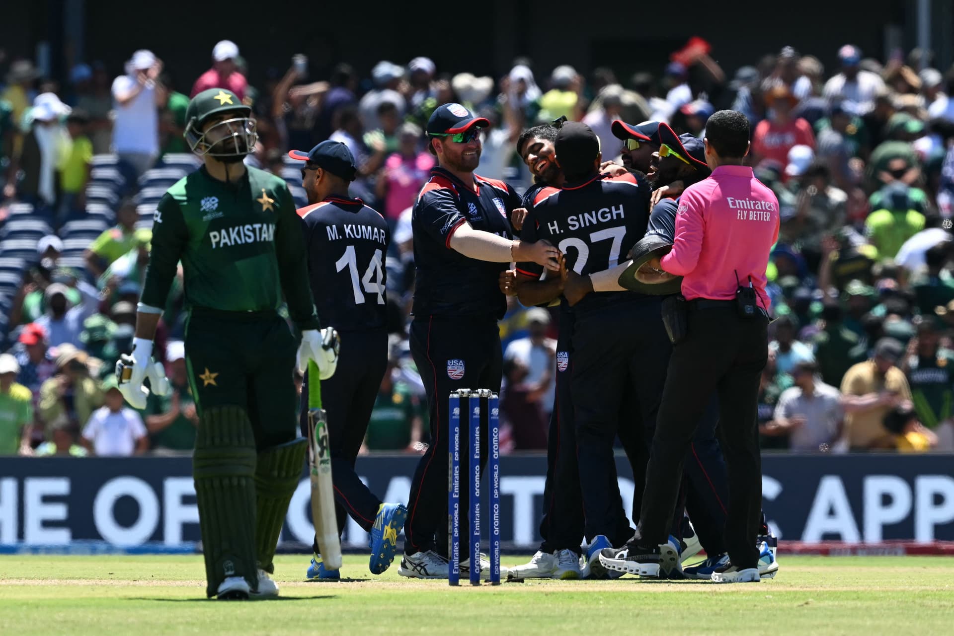 USA's players celebrate after winning the game in a super over as Pakistan's Shadab Khan walks off