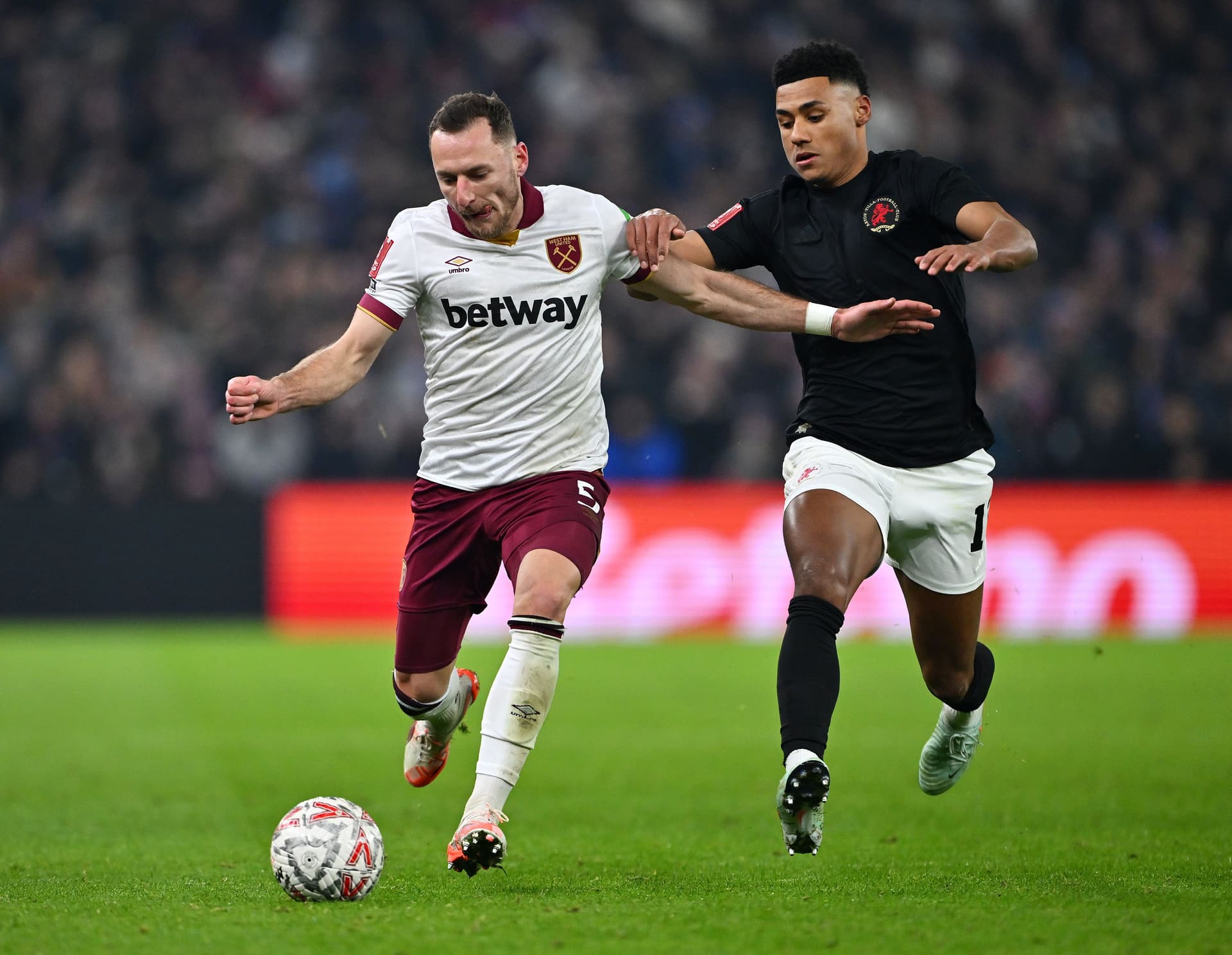 Vladimir Coufal runs with the ball whilst under pressure from Ollie Watkins